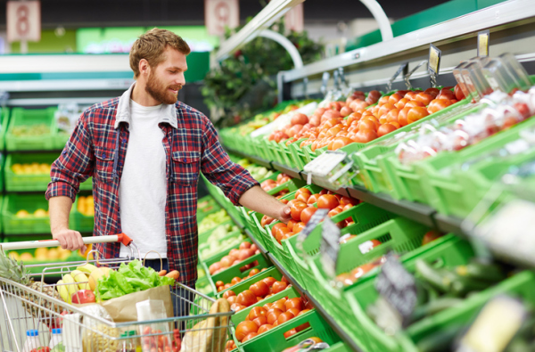 Man defining quality of tomato in supermarket